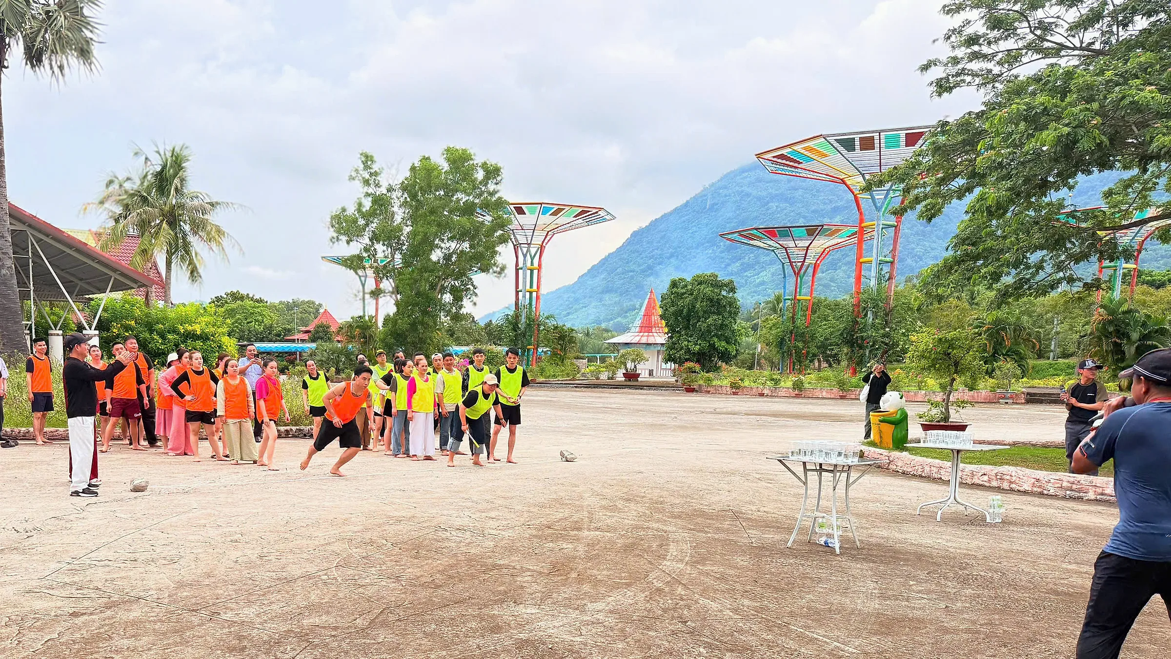 Đoàn chơi trò đồng đội trên sân Công viên Thanh Long, núi phía sau