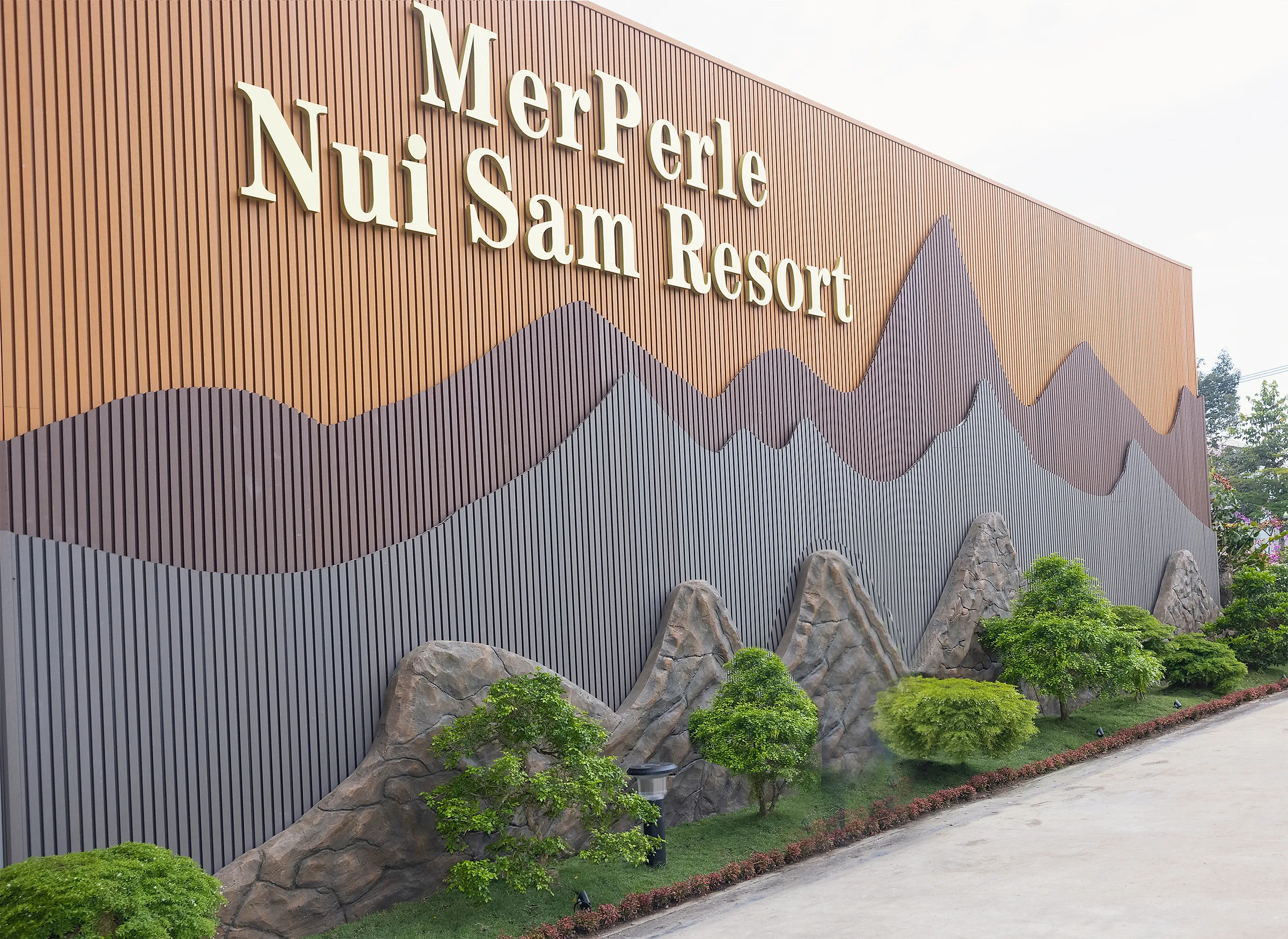 Tường tên MerPerle Nui Sam Resort ốp nan đất nung, phù điêu núi và tượng đá ở lối vào